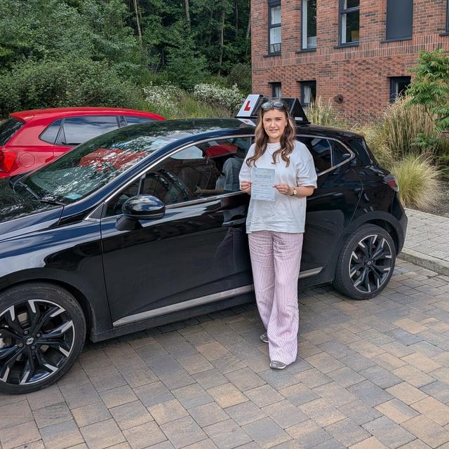 Pupil holding pass certificate beside the lesson car
