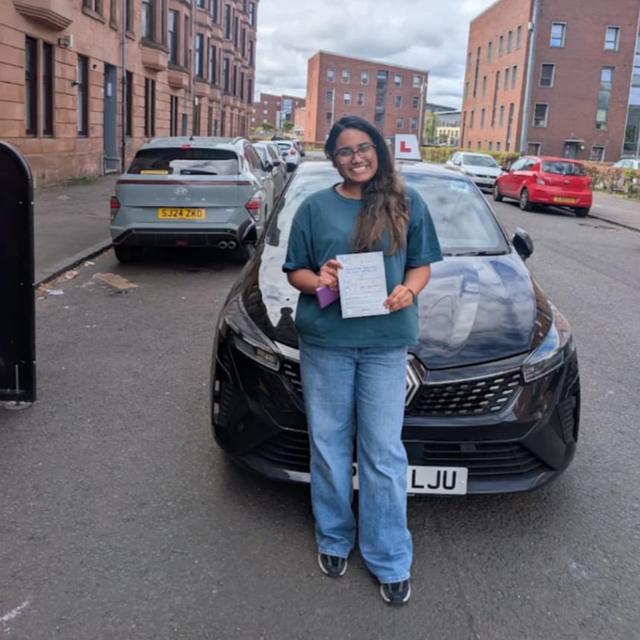 Pupil holding pass certificate in front of the lesson car