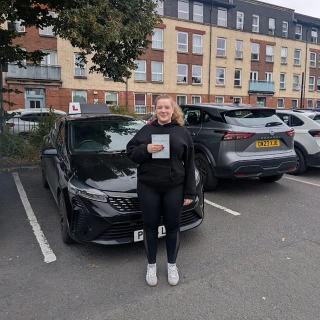 Pupil holding pass certificate beside the lesson car