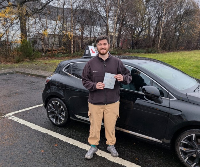 Pupil holding pass certificate beside the lesson car